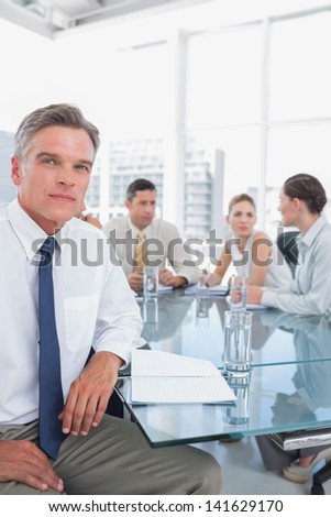 Serious businessman during a meeting with colleagues working behind