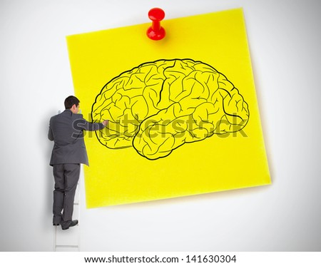 Businessman drawing a brain on a giant post it on white background