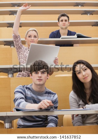 Four students sitting in a lecture hall while being attentive and participating