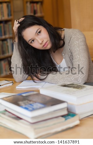 Student sitting at a desk in a library while learning and being stressed