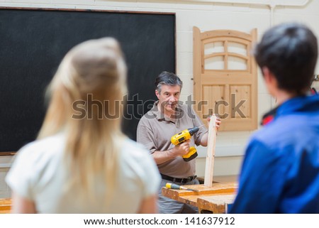 Two students of a woodwork class listening to the teacher who explaining