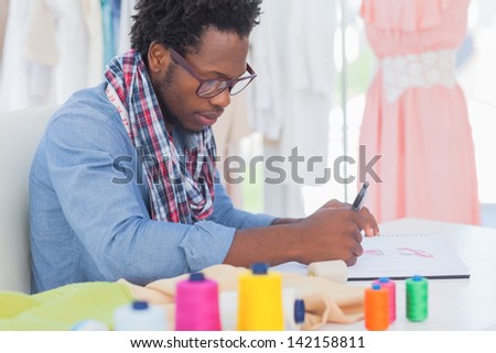 Fashion designer sitting at his desk drawing