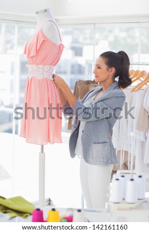 Fashion designer measuring dress with a measuring tape in a studio
