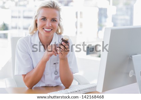 Smiling nurse sitting behind a desk and holding a medicine jar