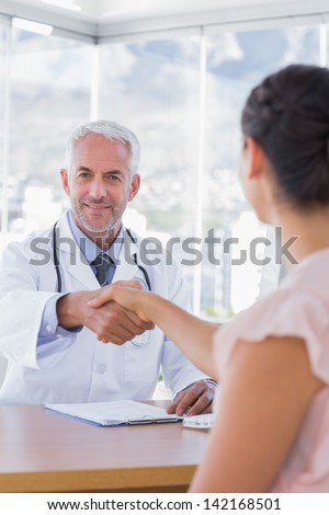 Cheerful doctor shaking hands to patient in the office