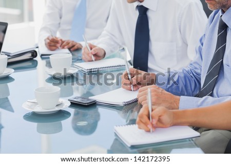 Business people taking notes on notepads during a meeting
