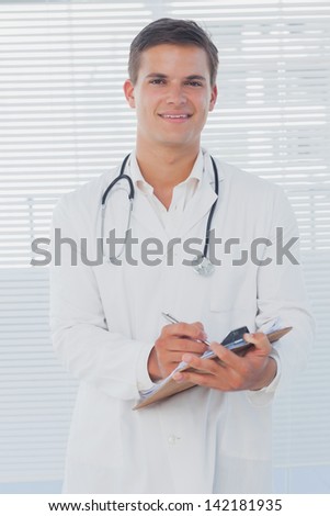 Handsome doctor holding a clipboard and writing