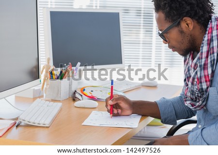 Handsome designer drawing something with a red pencil in a modern office