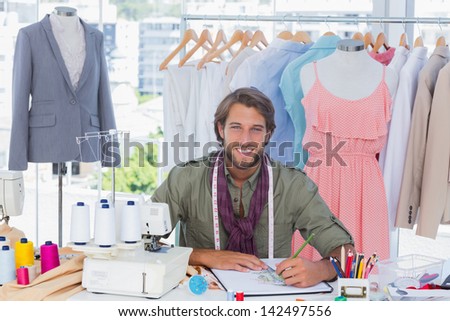 Attractive fashion designer drawing clothes and smiling to the camera