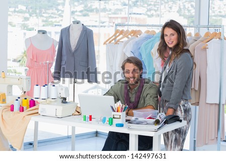 Young fashion designers working in a bright office and smiling to the camera