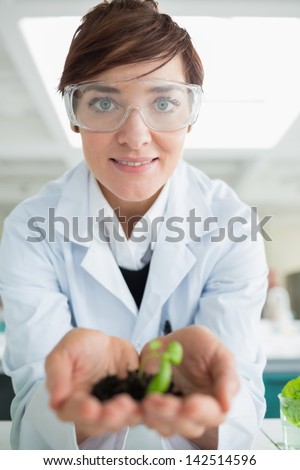 Smiling woman holding tiny plant in the lab