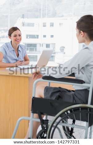 Businesswoman interviewing disabled job candidate in her office and smiling
