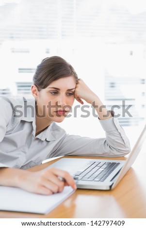 Fed up businesswoman at her desk looking at laptop