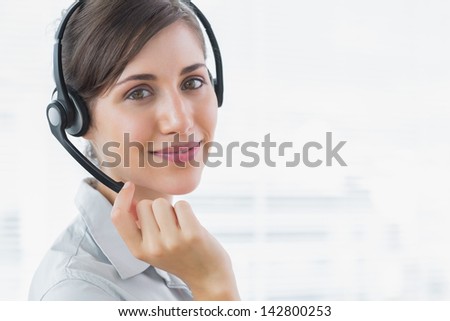 Pretty call centre agent smiling at the camera in an office