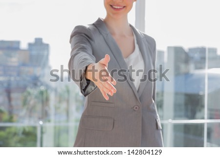 Businesswoman offering hand for handshake by a large window