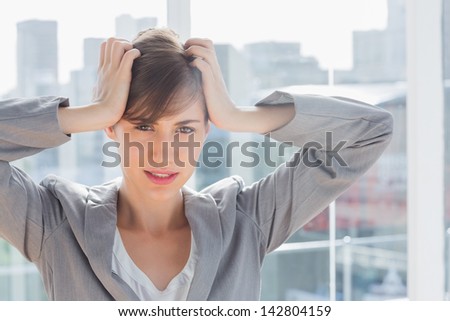Frustrated businesswoman looking at camera with hands on head