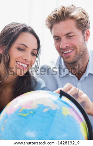 Happy couple looking at a globe in the living room