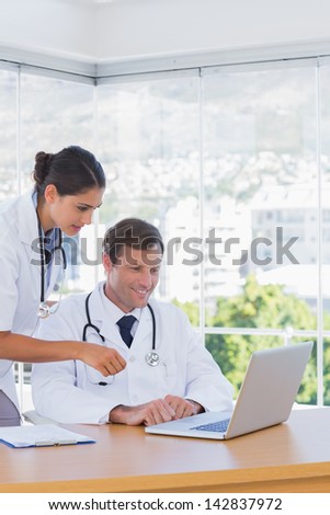Doctors working together on a laptop in a modern office