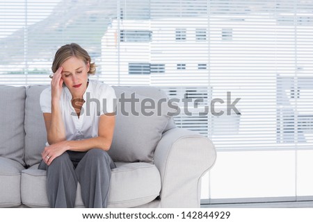 Businesswoman sitting on couch and getting headhache