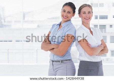 Businesswomen standing back to back and crossing their arms