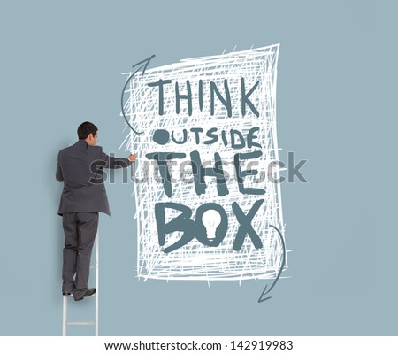 Businessman drawing think outside the box message on grey wall