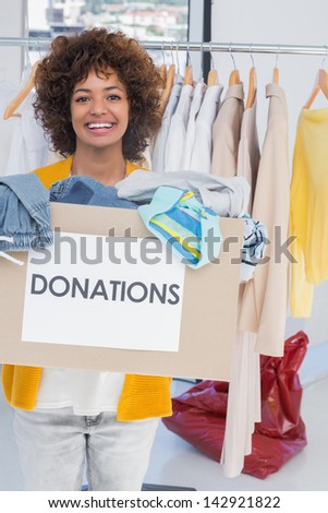 Young volunteer smiling and holding clothes donation box