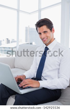 Smiling business man using laptop in a bright office