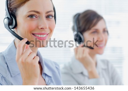 Smiling call centre agents with headsets at work in an office