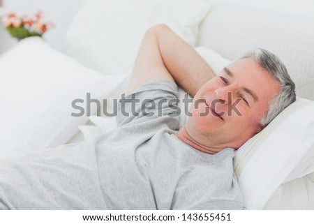 Smiling mature man relaxing in bed