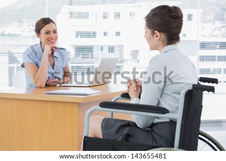 Businesswoman listening to disabled job candidate in her office and smiling