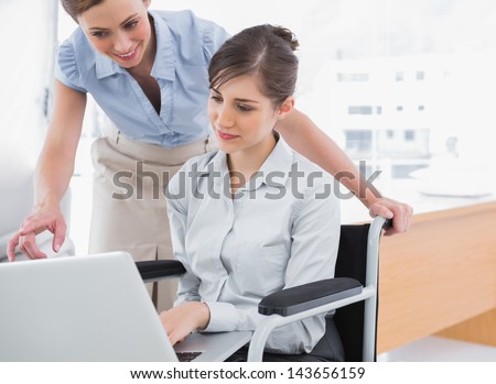 Disabled businesswoman showing co worker her laptop in the office