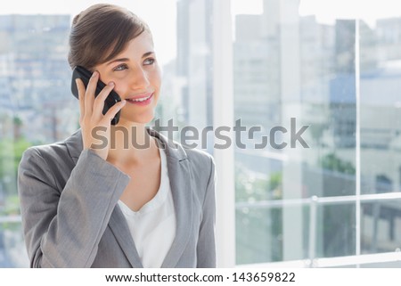 Businesswoman smiling and calling on phone in bright office