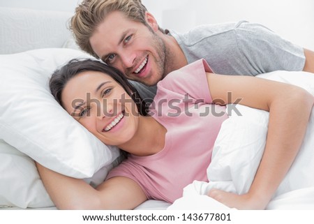Couple laughing and looking at camera in bed