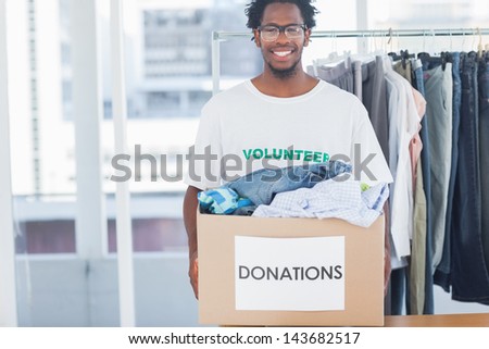 Attractive man holding a donation box full of clothes