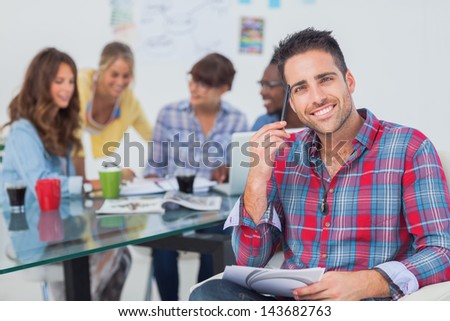 Handsome designer sit in his office with colleagues discussing behind