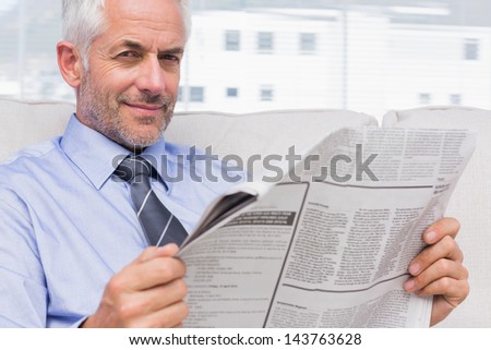 Smiling businessman holding a newspaper in office
