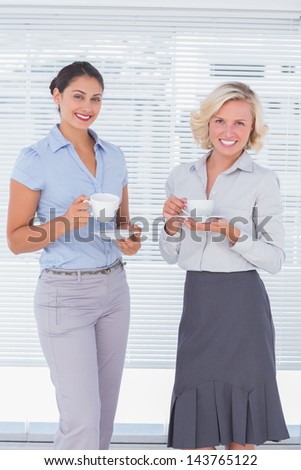 Two colleagues holding cup of coffee in the office