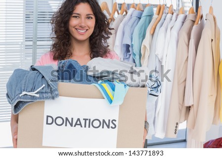 Pretty volunteer holding clothes donation box
