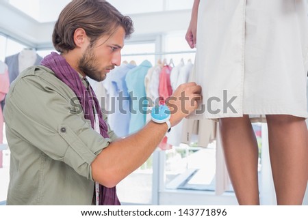 Concentrated fashion designer picking needles on dress