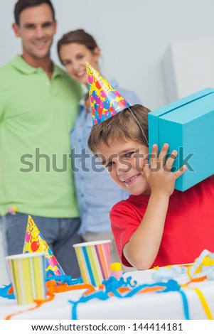 Little boy shaking his birthday gift during his birthday party