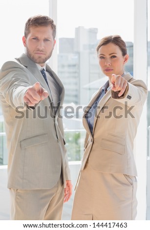 Serious business team pointing at camera in an office