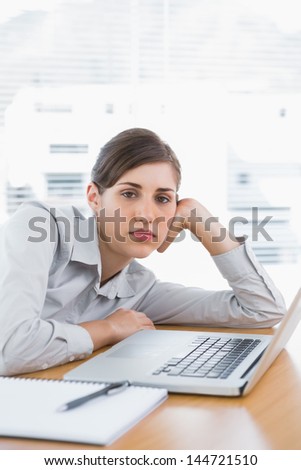 Fed up businesswoman looking at camera at her desk