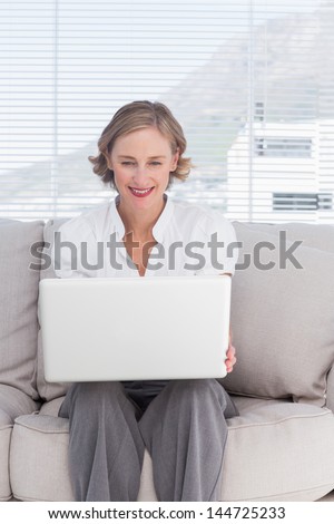 Portait of cheerful businesswoman with a laptop sitting on couch