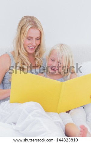 Mother reading a story to her cute daughter in bed