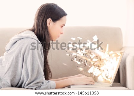Woman on the couch using laptop with binary codes exploding over