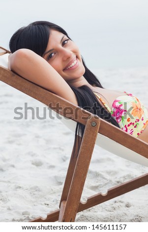 Beautiful woman resting on deck chair on beach
