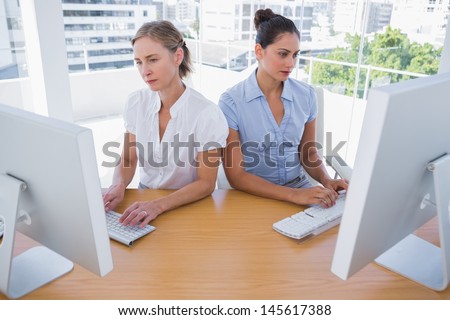 Businesswomen working side by side at desk in office