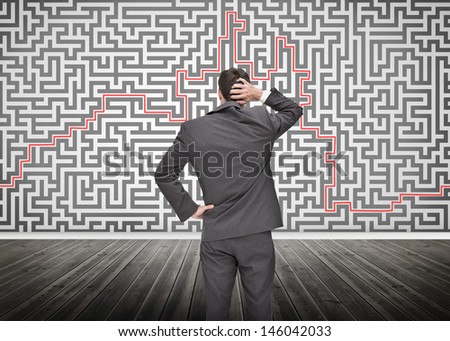 Puzzled businessman looking at a maze drew on a wall