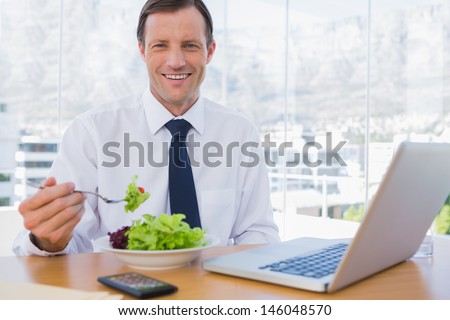 Happy Businessman Eating A Salad On His Desk During The Lunch Time