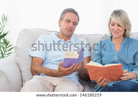 Couple talking about their books sitting on couch at home